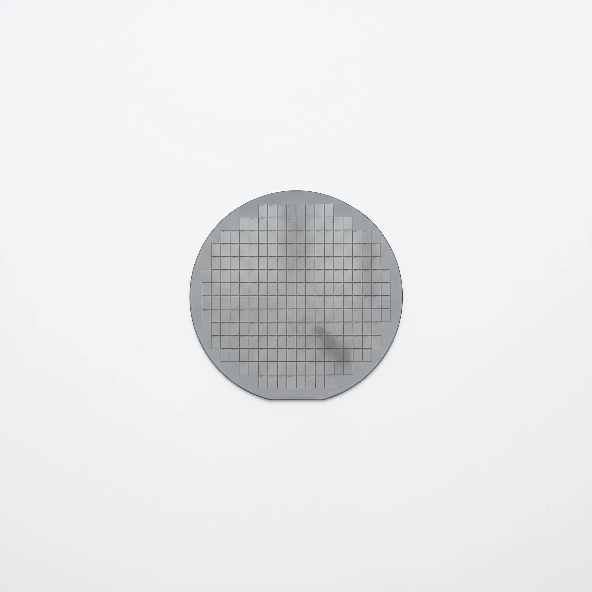 Macro of a silicon wafer's grid of dies on a white surface